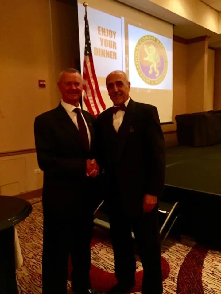 Two men in dark suits shaking hands at the ICHF 25th anniversary celebration.
