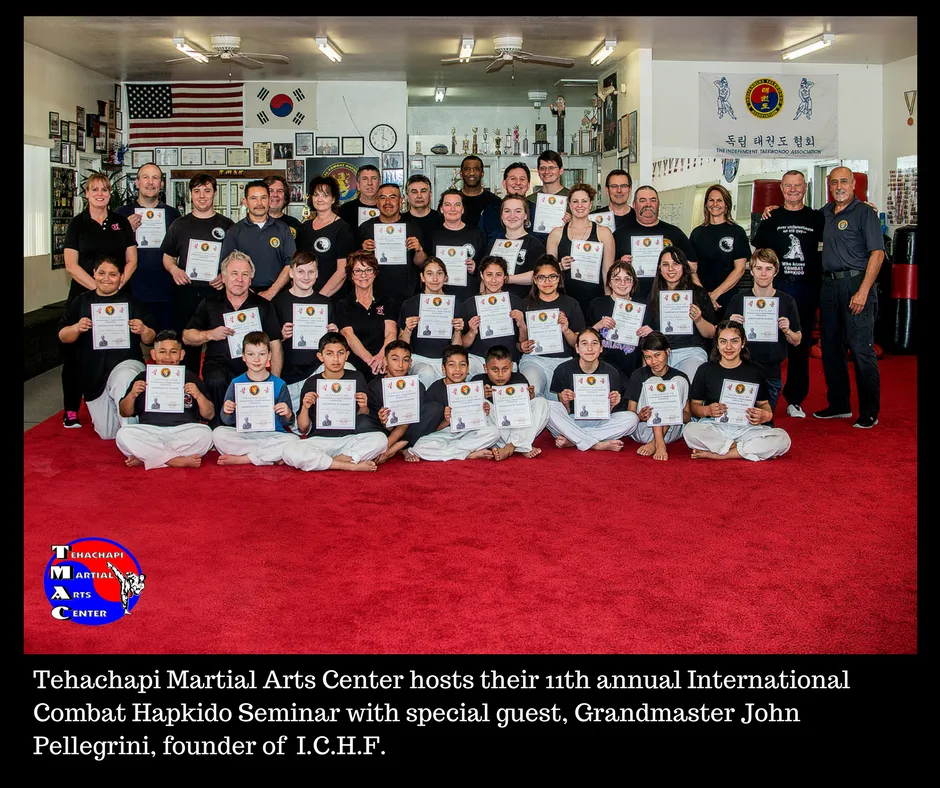 Attendees of the 11th annual Combat Hapkido seminar seated together on the red mat.